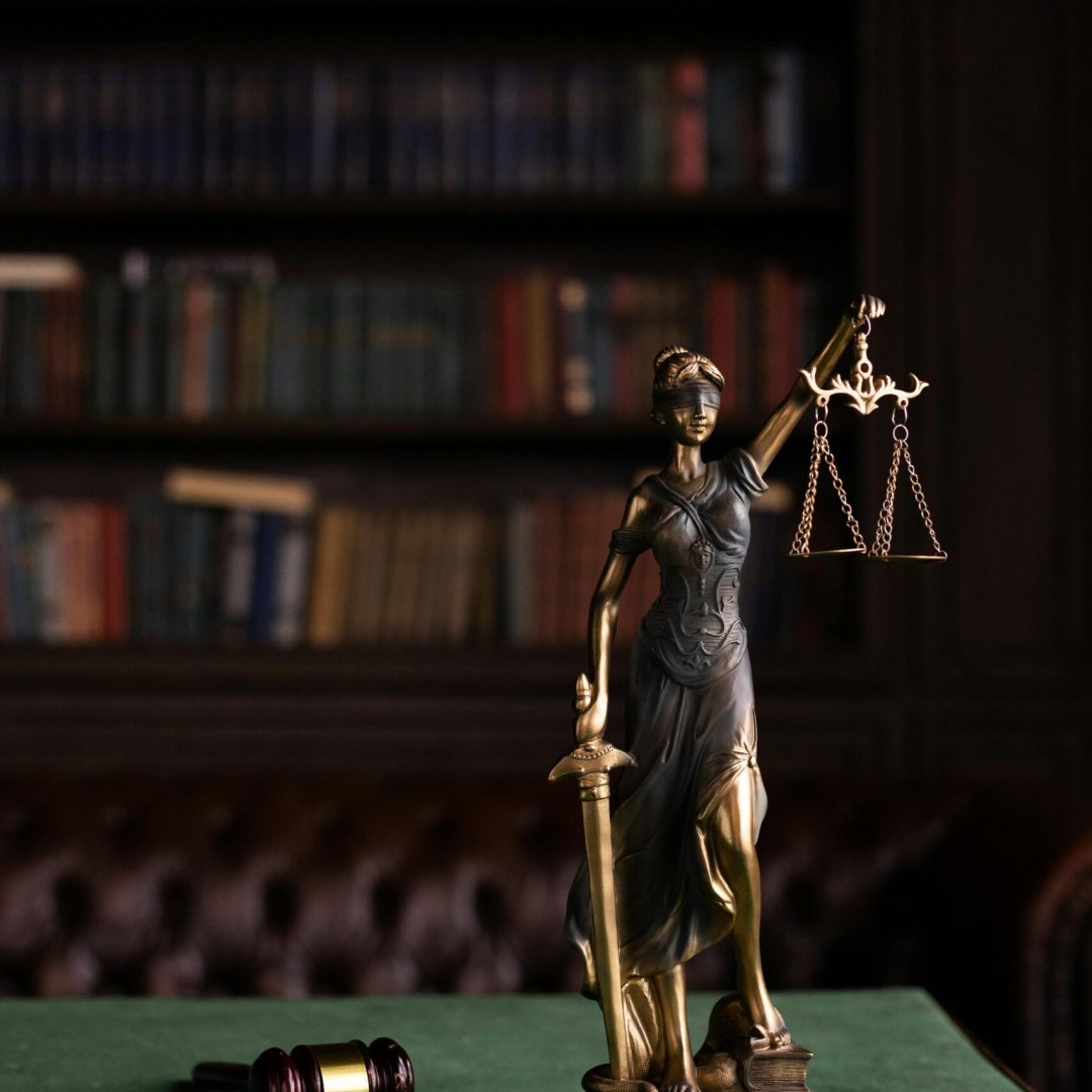 Lady Justice and gavel on a table in a classic law library setting.